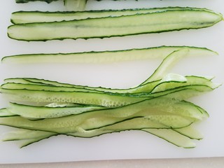 4、菠萝蛋包饭,黄瓜用刮皮器竖着刮成长条状，然后也切成食指宽的条。