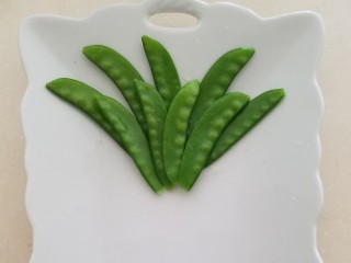 9、菠萝蛋包饭,荷兰豆洗净摘掉筋用开水焯烫后过凉控干水，在盘子里摆成菠萝叶子的形状，焯水时加些盐和食用油，这样焯完的荷兰豆颜色翠绿。