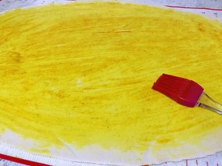 7、姜黄花卷,饮料做,在擀好的面饼上面,拿刷子刷上刚才调好的姜黄油,刷得均匀一致。