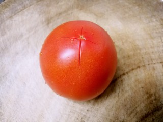 1、番茄鸡蛋牛肉粉,用刀在番茄底部划十字。