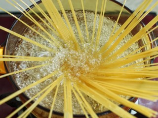 5、奶油蘑菇培根意面,锅中烧开水放一茶匙盐,再滴入少许橄榄油,将意面如图中呈放射状放入锅中煮12分钟左右