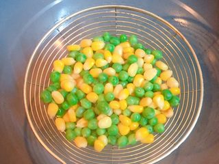 3、炒饭秀+五彩炒饭,锅中倒入适量清水烧开,将玉米粒和豌豆倒入锅中焯熟后,捞出沥干水分备用。