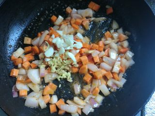 5、剩米饭华丽大变身——虾仁焗饭,接着放入红萝卜丁,翻炒两下,放入蒜片姜末翻炒均匀。