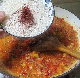 10、西班牙海鲜饭,放入2小勺的红椒粉, 倒入西班牙米和藏红花翻炒