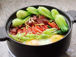 15、腊肠煲仔饭,请香肠熟透，鸡蛋也成型了，把青菜码到砂锅里撒上葱花，均匀的浇上汤汁，