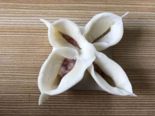 7、四喜蒸饺,再将相邻的两条边捏合，再把每个花瓣捏个尖角出来，如图;