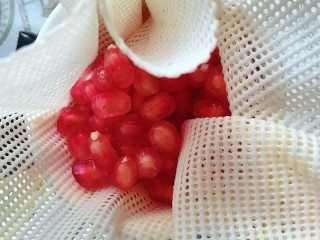 6、石榴气泡鸡尾酒,留出10余颗石榴粒,将其他石榴粒包入容器上的屉布里,用手用力挤压