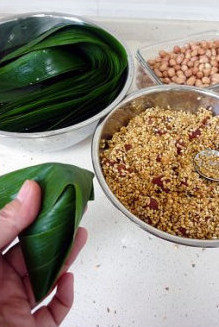 5、香浓里脊肉粽,用右手将漏斗后面的苇叶盖在糯米上，然后左手拇指跟食指将漏斗两边卡住，这样就基本定型成四角粽了。