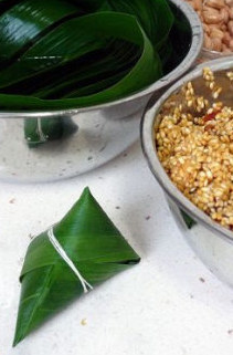 7、香浓里脊肉粽,将棉绳的一端用牙咬住，另一端将粽子缠紧扎结实即可，最后可将多余的苇叶剪掉。