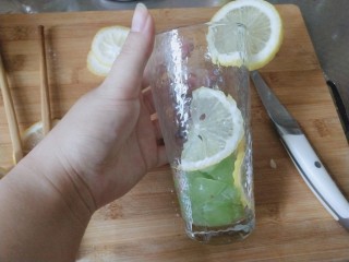 3、青提柠檬气泡水—夏天的快乐,准备一个玻璃杯，先放青提，用筷子或者其他工具把青提碾碎，柠檬贴在杯壁上