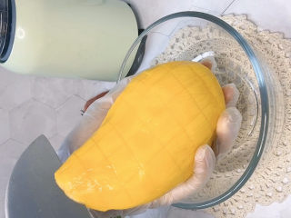 7、芒果西米捞,改花刀以后，用中间沿着果核对半切开，两面一样的做法，这样完整的果肉就切好了。