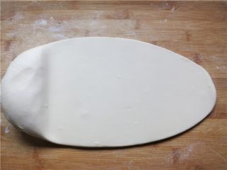 4、教你做一碗销魂的油泼面,面板上撒少许薄面，把面团放在上面，用擀面杖擀成厚0.5cm左右的面片，用保鲜膜或者潮湿布盖好饧5分钟左右