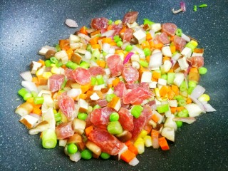 3、香到流口水的香菇腊肠焖饭,热锅热油，加入洋葱爆香，加火腿炒至透明色，依次加入香菇、豌豆、玉米、香干、胡萝卜、芹菜翻炒均匀。