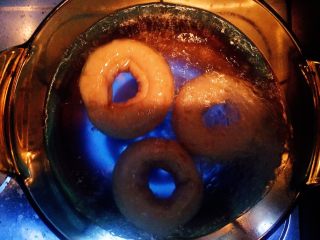 12、燕麦芝士贝果～,等到糖水沸腾了，就把发酵好的圆胖子放入水中开始煮，两面分别煮30秒-1分钟～然后用漏勺捞出来放在烤盘上～在煮糖水的同时把烤箱进行预热～