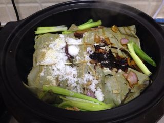 11、荷香卤鸡腿,把捆好的鸡腿包放进砂锅里，倒入香料、大葱、和剩余的老抽、白糖、盐、料酒，还有腌汁一起倒入电砂锅里