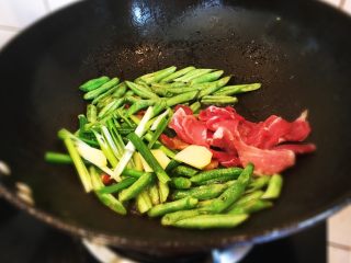 6、豆角焖面,加入葱姜和瘦肉片继续炒匀。