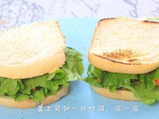 8、牛油果鸡蛋火腿三明治,如果还有火腿再铺一片,再铺上一层生菜。另外一片吐司再抹上一层坚果酱。坚果酱不仅营养更丰富,也使三明治上升了口感,吐司片盖上,压一压。