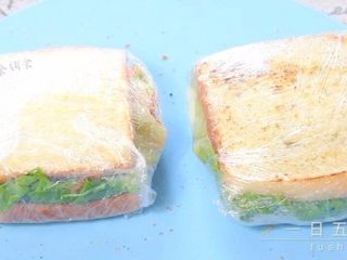 9、牛油果鸡蛋火腿三明治,将组合好的三明治放在保鲜膜上。卷起来,尽量卷的紧一些。如果是带出门或者第二天吃这样就可以了。