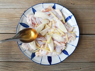 4、苹果烧鸡翅,将葱姜铺在打过花刀的鸡翅上，加两小勺料酒，抓拌均匀，腌制15分钟。