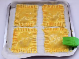 11、馄饨皮香蕉派,烤盘铺油纸放入做好的香蕉派，表面刷上蛋黄液。