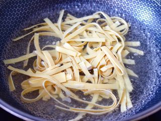 7、豆皮黄花鱼,腌制黄花鱼的时候,锅中倒入适量清水烧开,把豆皮放入锅中开始焯水。