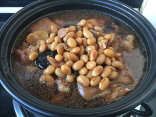 16、美容养颜养生菜 黄豆煲猪手,将步骤18一部分的猪手黄豆连同汤汁放入砂锅里。