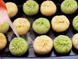 20、双色西葫芦韭菜生煎包,看见包子底下定型后，用少许面粉加清水和成水状，倒入锅中后，小火慢慢煎制。