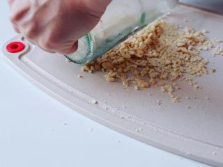 2、潮汕毂（ka）蜡李,碾碎花生米，如果家里没有搅碎工具，可以像我们一样，在砧板上放花生米，用玻璃樽碾碎即可。