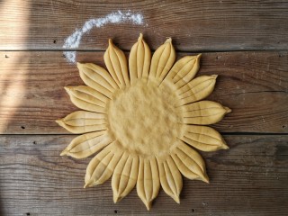 7、春暖花开,把每三份末端捏起合在一起，圆饼中间部分按压下去做成葵花盘子造型。