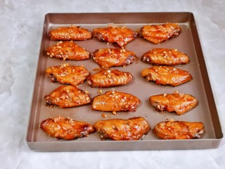 12、蒜香鸡翅,取出刷上蜂蜜，再刷上腌制剩下来的蒜泥，撒上白芝麻，入烤箱再烤10分钟。