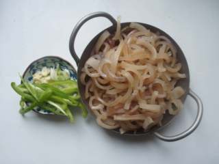 5、香辣猪皮黄豆,猪皮煮好后晾到还有些热度，但可以用手操作的时候，用刀刮去里层的白色油脂，只留下猪皮，切成条状。青椒切丝，葱花姜丝蒜片切好。