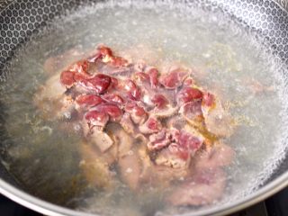 5、香脆椒爆蒜苔鸡肝,锅中倒入适量,加入1勺盐烧开,把腌制好的鸡肝下锅。