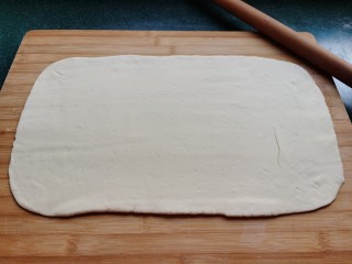 7、红糖花卷,发酵好的面团放到面板上，手揉排气，揉至面团光滑，用擀面杖擀成一个长方形的面片。