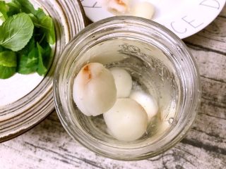 7、薄荷柠檬荔枝饮,选择两个漂亮的水杯,分别倒入400毫升纯净水,分别放入4个冻荔枝