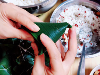 9、红豆粽子,再将长叶部分翻转将粽子包起来。