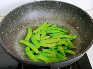 5、荷兰豆炒虾仁,将荷兰豆焯水，锅中加入水烧开，下荷兰豆，煮断生，捞出淋干水分。