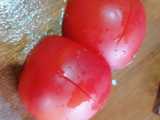 5、番茄豆腐汤,番茄清洗干净再切成两半,在面上划一刀