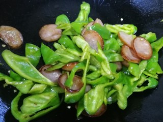 12、青椒炒香肠,把螺丝椒和香肠文火翻炒均匀。