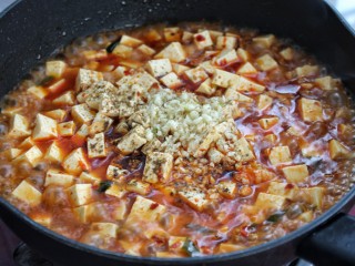 12、家常麻辣豆腐,加入蒜末和花椒粉，晃动锅子使豆腐与蒜末、花椒粉混合均匀