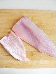 6、水煮鱼,一手用刀将鱼腹部分的鱼骨及鱼腩片下来