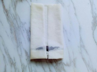 7、炸春卷,再将两边对折，如图。卷起来，卷到末尾的时候，涂抹上一点面糊。