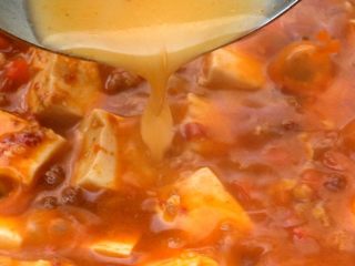 13、麻婆豆腐,调入适量的生粉水,用勺子轻轻搅动至汤汁浓稠,小火慢煮至重新烧开就能关火了。
