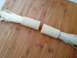 5、【豆皮金针菇卷】,将豆皮卷起，卷向另一端，要卷紧，用刀在豆皮卷中间切开，一分为二