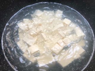 4、番茄烧豆腐,锅里放入一碗水烧开，加入一勺盐搅拌融化，把豆腐放入焯3分钟（豆腐焯一下可以去除豆腥味，而水里加一勺盐，烧的时候豆腐不容易碎掉），豆腐焯好捞起来沥干水待用。