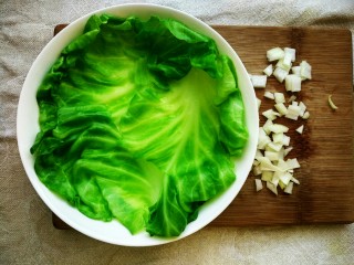 3、不甘平凡的番茄炒蛋,最后准备三片相对完整的甘蓝叶子，洗净后用开水焯烫熟透，均匀地摆在盘中备用。顺便再将一片洋葱切碎。