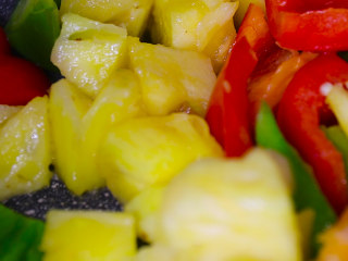 9、酸甜可口的菠萝咕噜肉,炒锅中放少量油,油热后放入甜椒和菠萝炒出香味后盛出