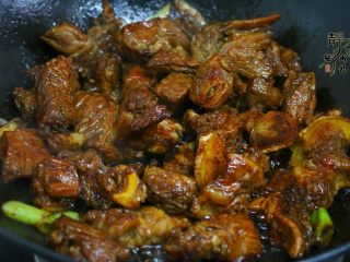 7、好看更好吃的红烧牛肉面,然后放入葱和姜片，调入黄酒和红烧酱油，快速炒匀炒香。