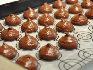 23、浓情巧克力无比派,烤盘内铺上马卡龙硅胶垫,将面糊均匀的挤到烤盘上。