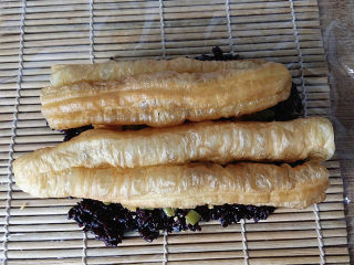 9、双糯米蒸饭包油条,将油条一拽两半平铺、用手将油条捏紧些