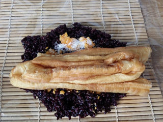 12、双糯米蒸饭包油条,同样将油条一拽两半平铺、用手将油条捏紧些